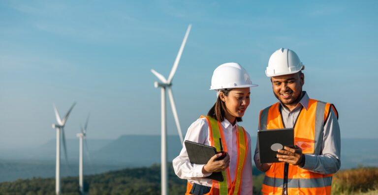 Workers monitoring wind farm in hi vis