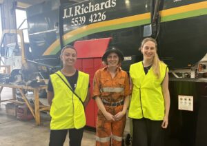 Three tradeswomen standing in front of large truck