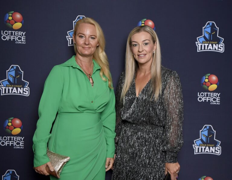 Two women standing in front of Gold Coast Titans media wall for 2024 season launch