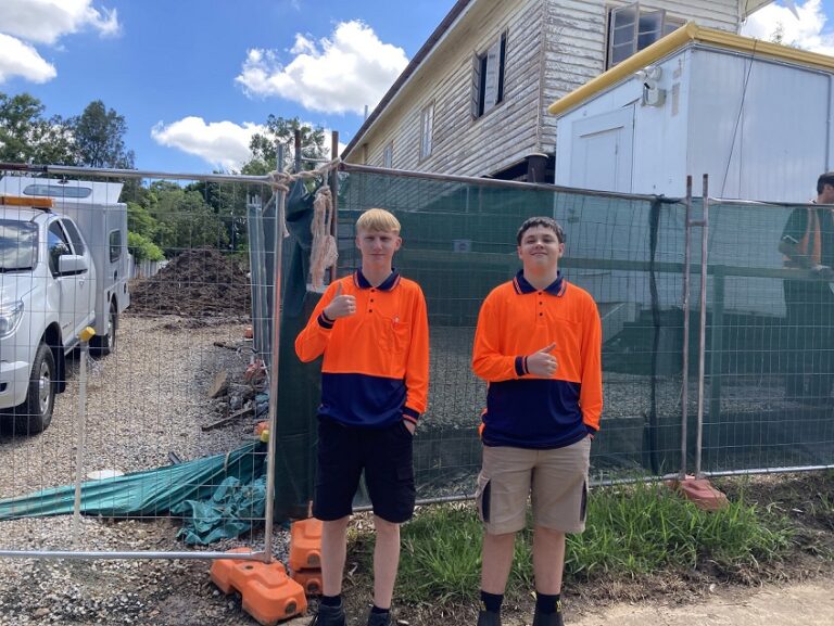 Two young tradies standing in front of a building site